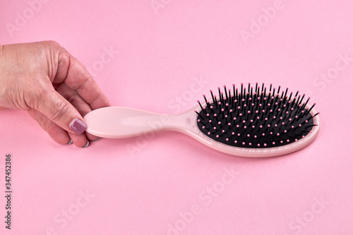 woman take a pink hairbrush isolated on a pink coral background with space. beauty hair accessory for hairstyle.