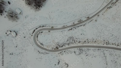 Aerial view of car on winding road amidst snow covered land, drone on top of curve highway - Jackson, Wyoming photo