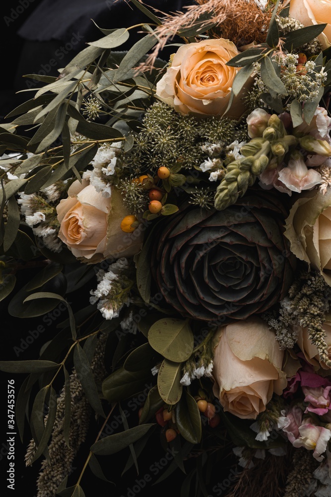 Vertical closeup shot of a luxurious bouquet of orange and brown roses on a black background