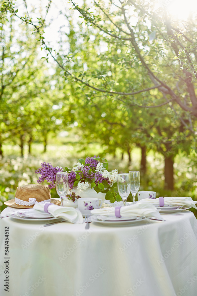 Holiday decorated dining table in the spring garden.  Lilac flowers in vases on the table. Purple style. French Provence