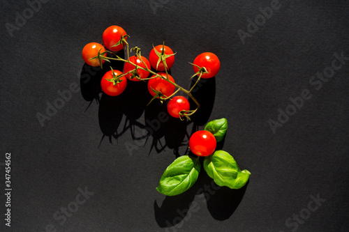 red tomatoes cherry with basilica on black background  photo