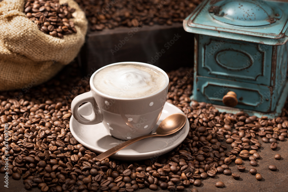 Hot coffee cup cappuccino or latte, roasted beans and old grinder. Rustic Coffee background