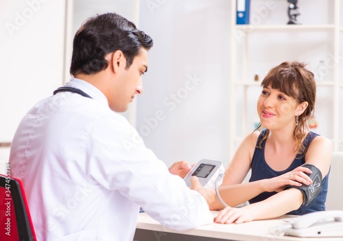 Young doctor checking woman s blood pressure