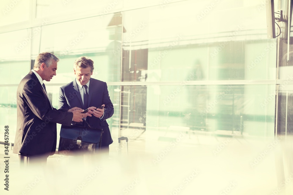 Portrait of businessmen talking while waiting for taxi in airport Portrait of businessmen talking while waiting for taxi in airport