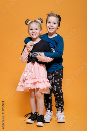 boy hugs a girl,  brother and sister on yellow background photo