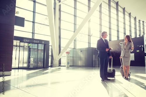 Portrait of business people walking while talking in airport