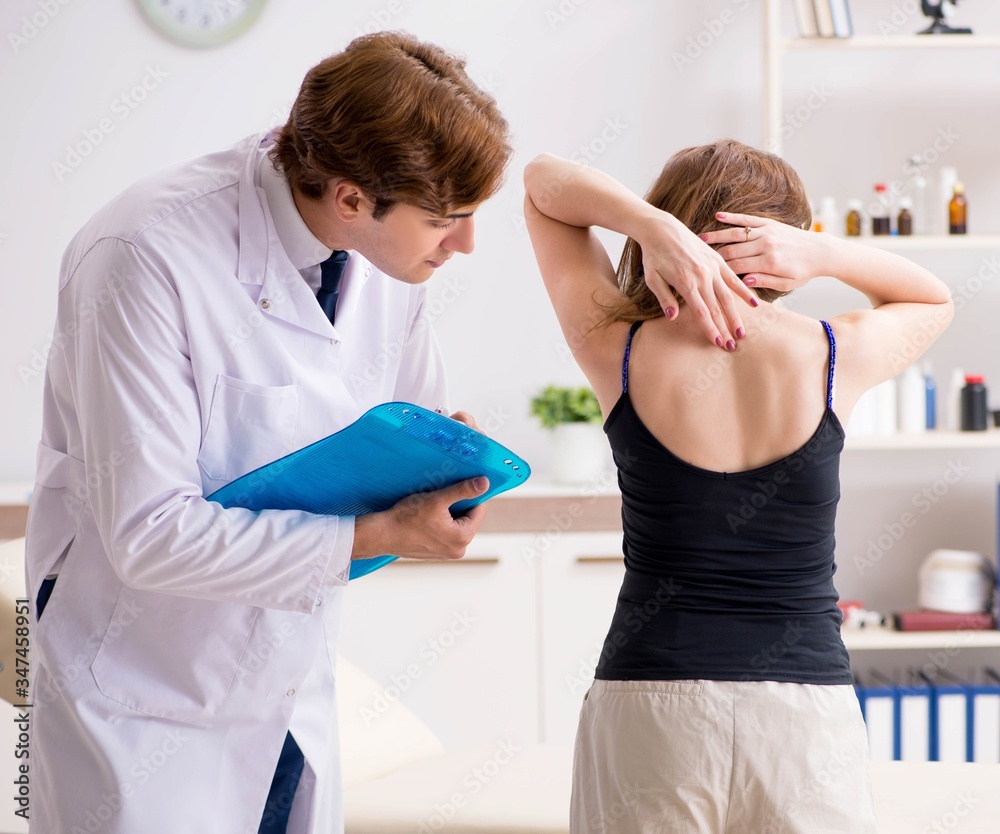 Obraz premium Female patient visiting young handsome doctor chiropractor