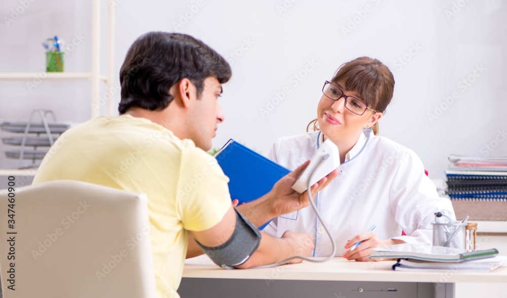 Fototapeta premium Young doctor checking patients blood pressure
