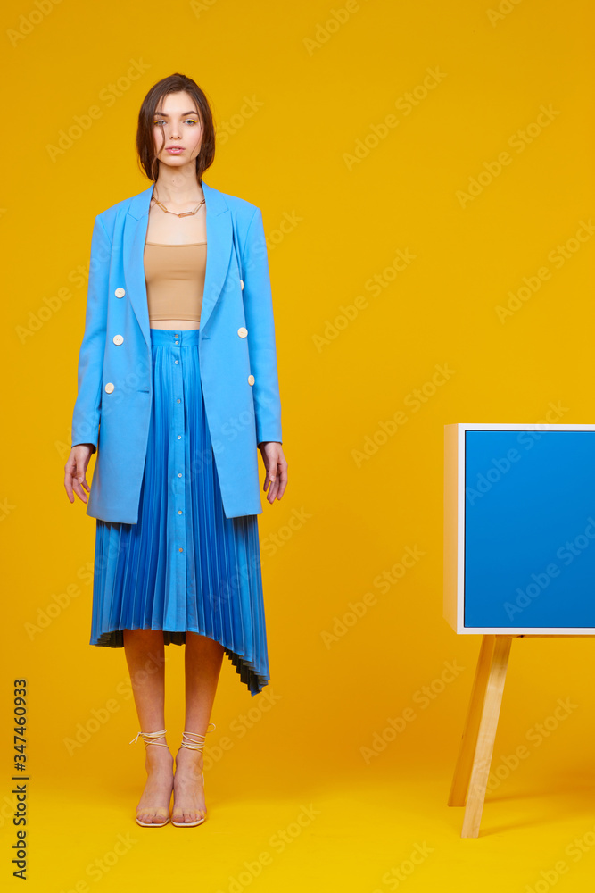 High fashion portrait of young elegant woman in blue jacket and skirt.