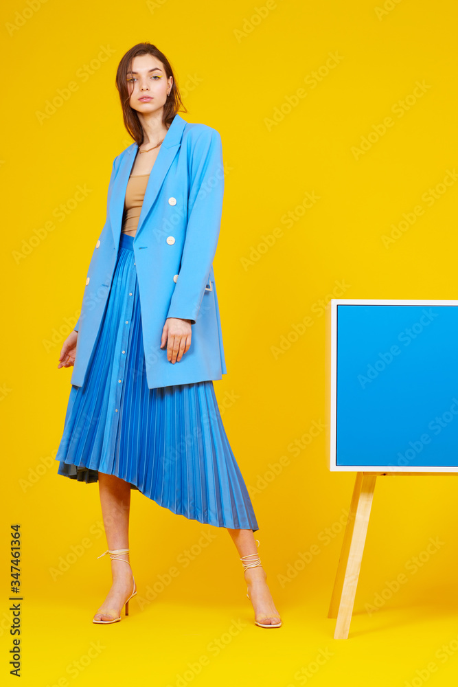 High fashion portrait of young elegant woman in blue jacket and skirt. High fashion portrait of young elegant woman in blue jacket and skirt.