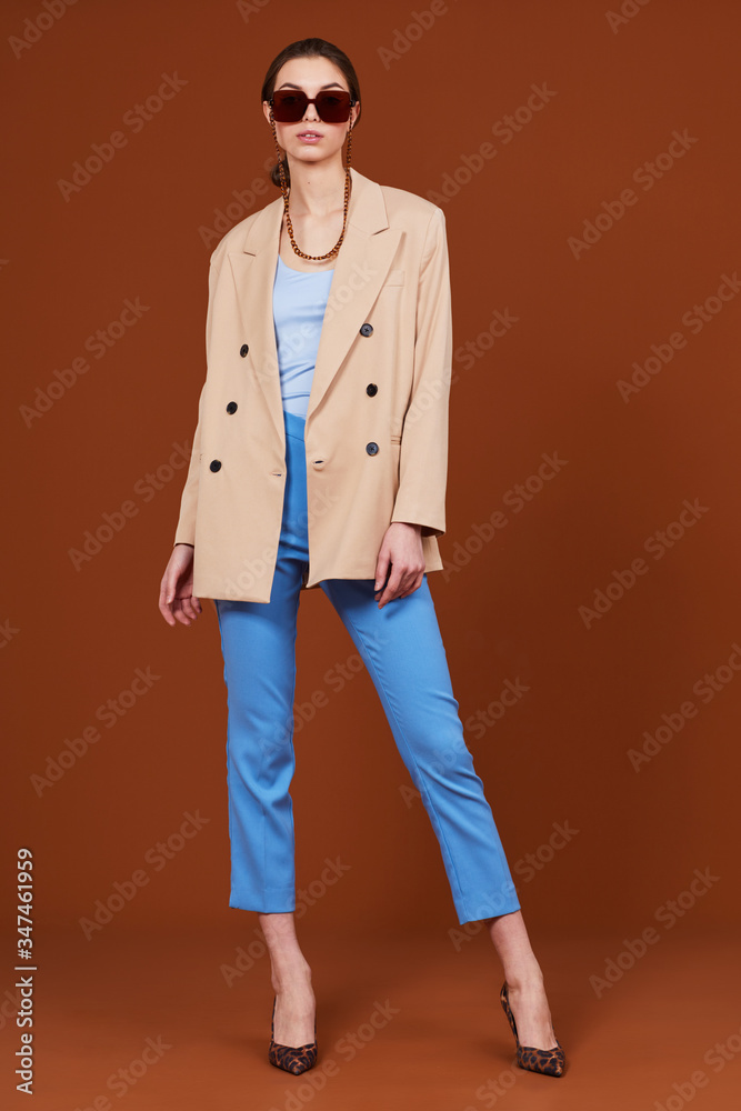 High fashion portrait of young elegant woman in beige jacket and jeans. High fashion portrait of young elegant woman in beige jacket and jeans.