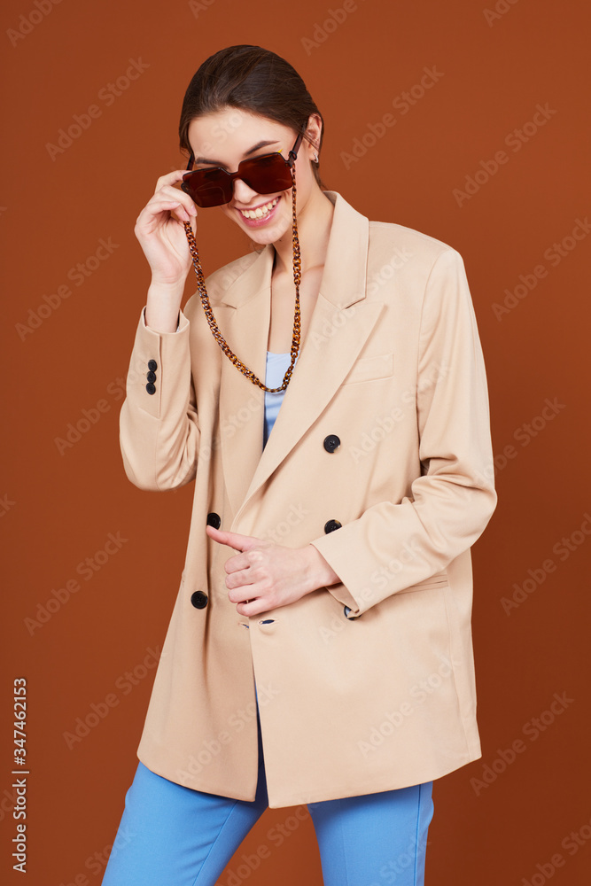 High fashion portrait of young elegant woman in beige jacket and jeans.