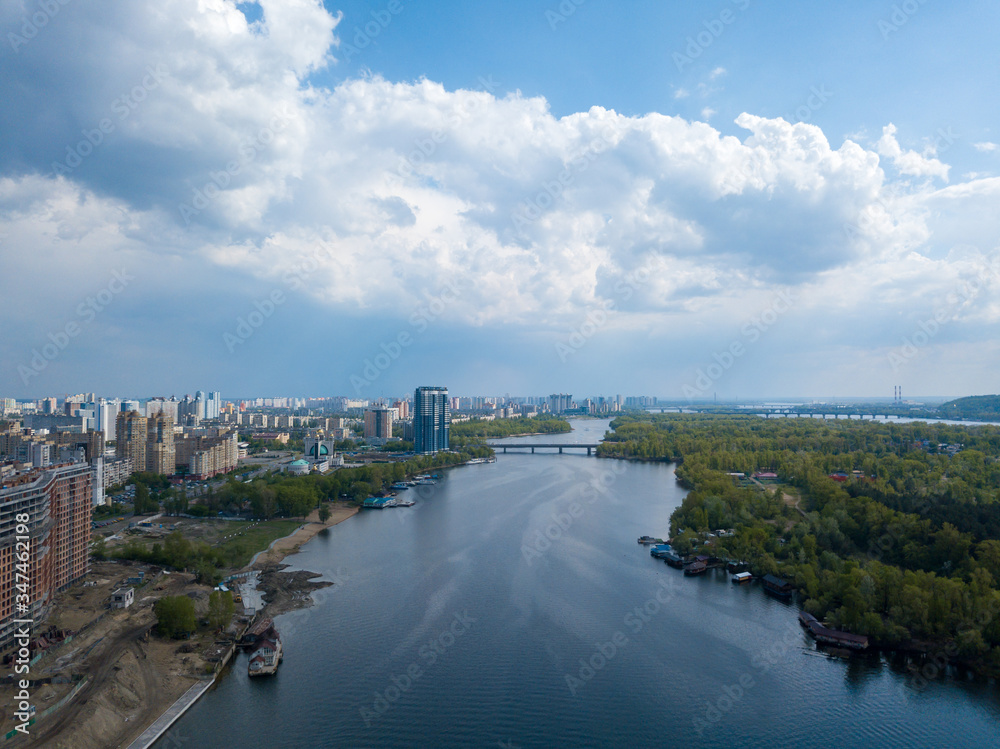 View of the Dnieper River in Kiev. Green trees on the banks of the river. Sunny spring day. Aerial drone view.