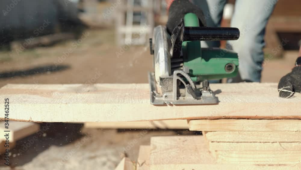 A man is sawing a board. Work with a tree. Saw boards. Build a house. Hand electric saw. Work carpenter. Do it yourself. A man is sawing a board. Work with a tree. Saw boards. Build a house. Hand electric saw. Work carpenter. Do it yourself.