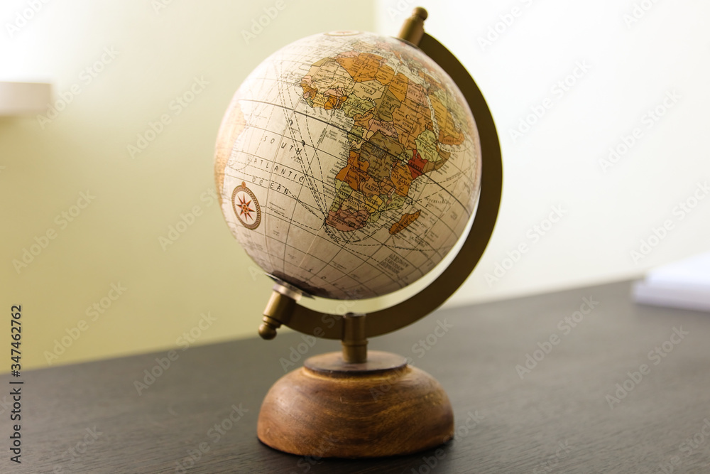 Globe model on the dark wooden table in the room Globe model on the dark wooden table in the room