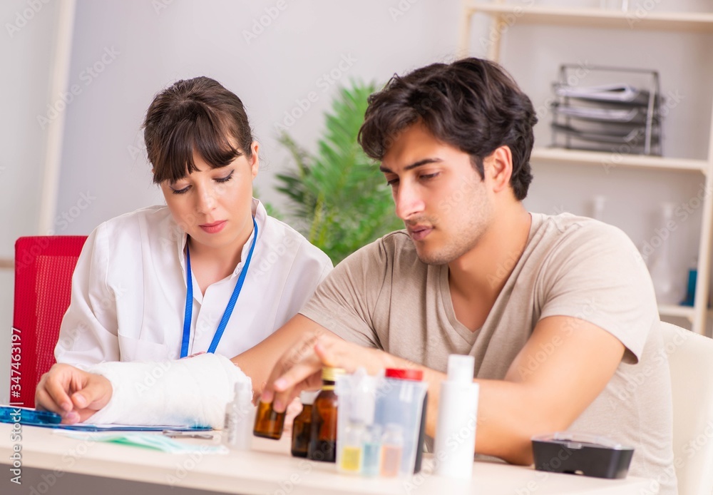 Young man with bandaged arm visiting female doctor traumatologis Young man with bandaged arm visiting female doctor traumatologis