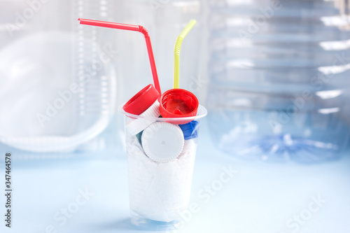 Danger cocktail from plastic bag and bottle caps with colorful straw against plastic. Concept of environmental pollution with plastic.