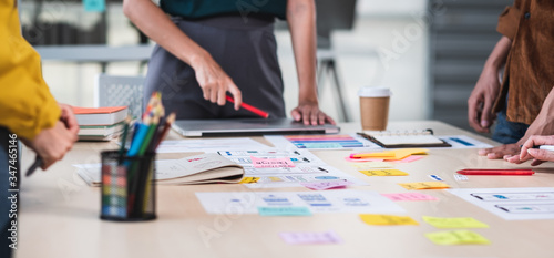 Close up ux developer and ui designer brainstorming about mobile app interface wireframe design on table with customer brief and color code at modern office.Creative digital development agency.panning photo