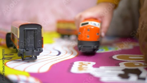 hands of lovely blue-eyed blond Caucasian boy playing with a toy train