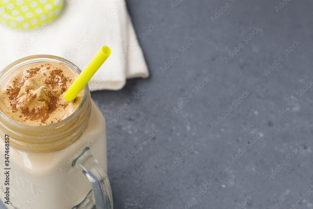 Iced Dalgona Coffee, a trendy fluffy creamy whipped coffee. Glass mug, cotton napkin close-up on a gray background. Horizontal position. Copy space. Iced Dalgona Coffee, a trendy fluffy creamy whipped coffee. Glass mug, cotton napkin close-up on a gray background. Horizontal position. Copy space.