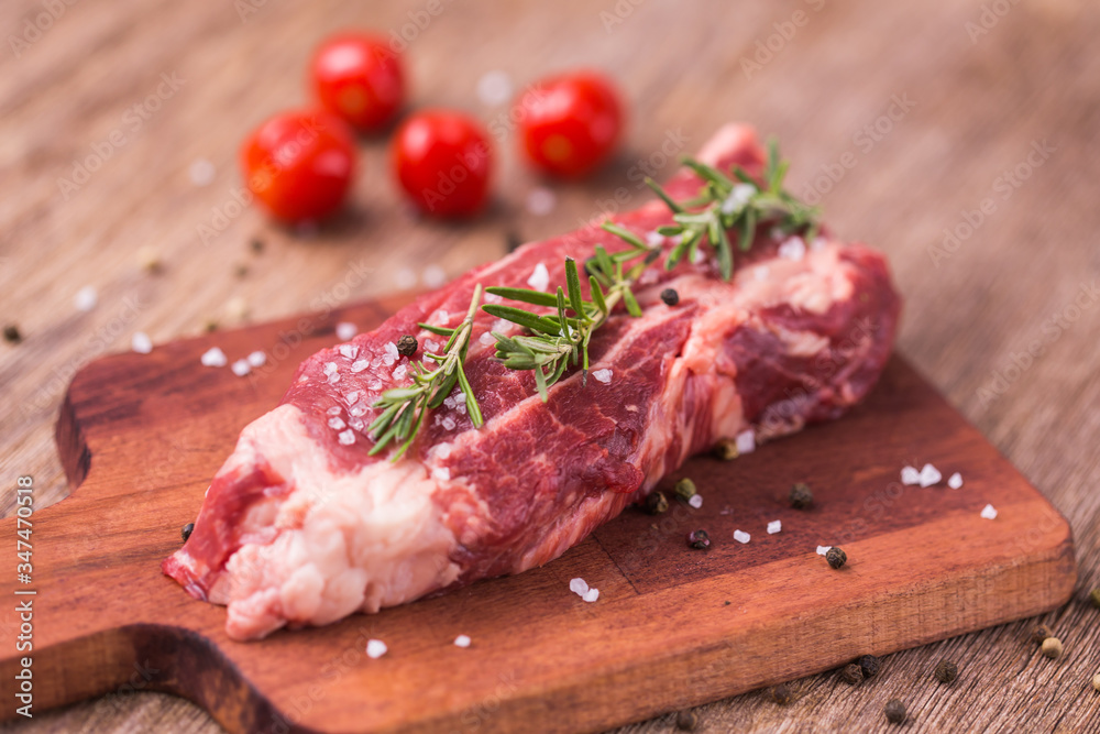 Raw beef fillet steaks with herbs and spices on wooden background