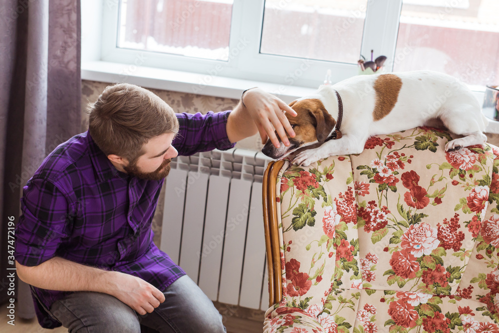 Φωτογραφία Close Up portrait handsome young hipster man plays and loves his good friend dog at home