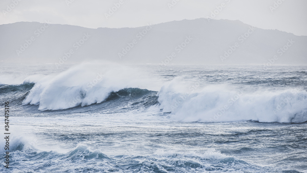 Big waves hit the rocks in rough seas. On a cloudy day. Galicia Spain.