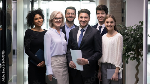 Foto 60s and millennial company staff members standing in hallway photo shooting for corporate album