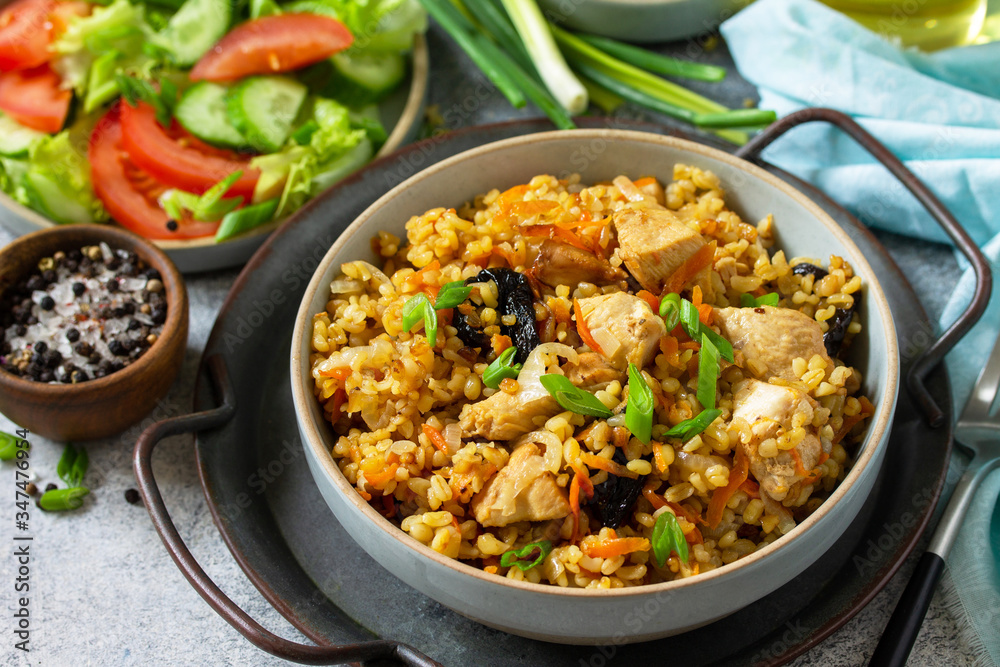 Bulgur pilaf. Healthy eating concept. Bulgur with chicken, vegetables and prunes on a gray stone or slate countertop. Bulgur pilaf. Healthy eating concept. Bulgur with chicken, vegetables and prunes on a gray stone or slate countertop.