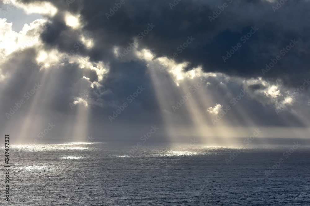 Rays of light that pass over the clouds and illuminate the sea like spotlights. Concept of nature and sea. Galicia, Spain