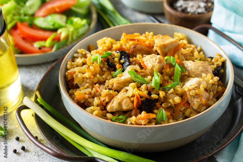 Bulgur pilaf close-up. Healthy eating concept. Bulgur with chicken, vegetables and prunes on a gray stone or slate countertop.