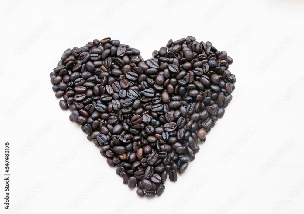 The shape of the heart is laid out on a light background of roasted coffee beans, there is room for text. The shape of the heart is laid out on a light background of roasted coffee beans, there is room for text.