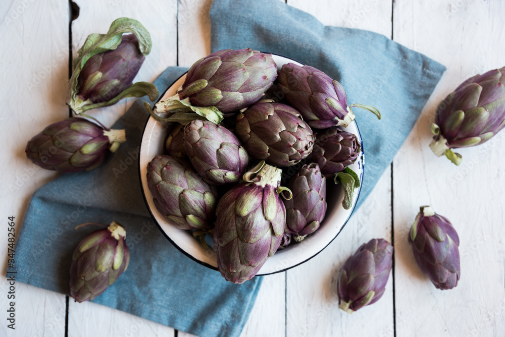 Fresh uncooked artichokes vegetables in a white bowl, healthy food Fresh uncooked artichokes vegetables in a white bowl, healthy food