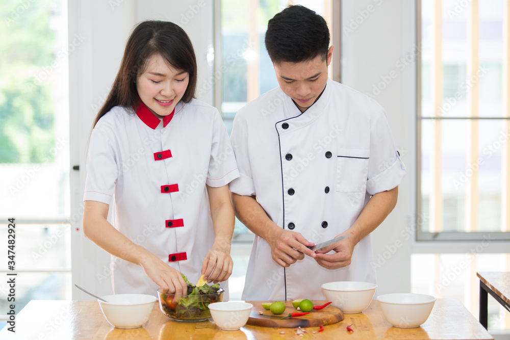 Two young Asian chefs helping each other Cook clean food with joy. Two young Asian chefs helping each other Cook clean food with joy.