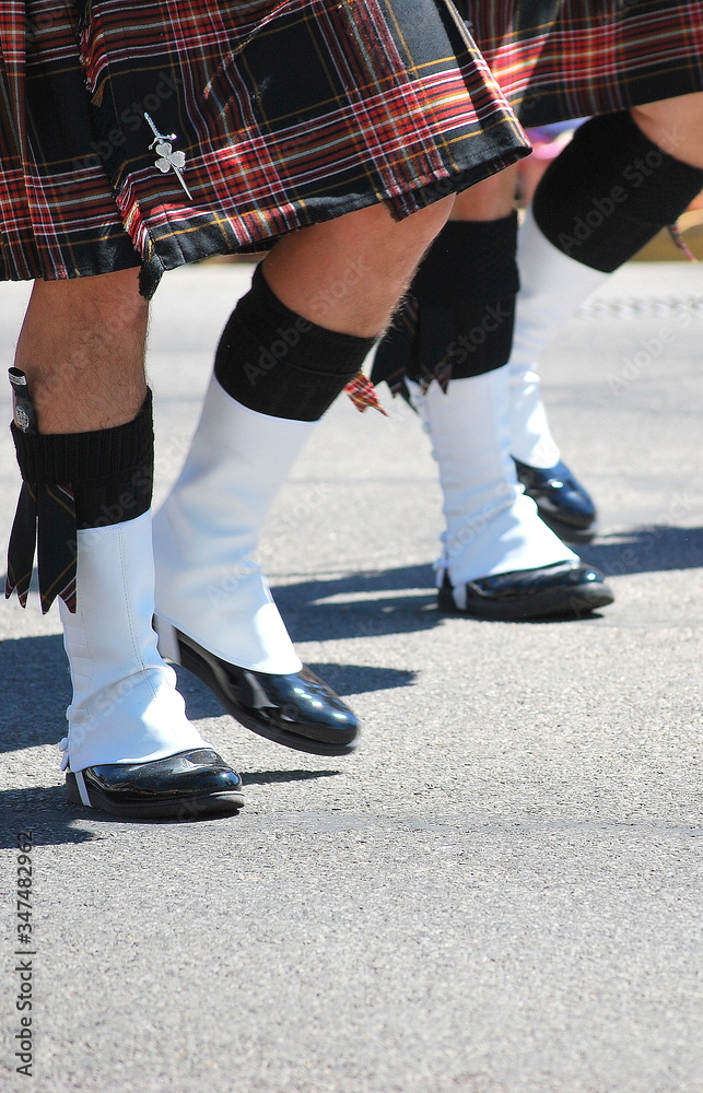 Scottish bagpipe marching band performing in a parade outdoors. Scottish bagpipe marching band performing in a parade outdoors.
