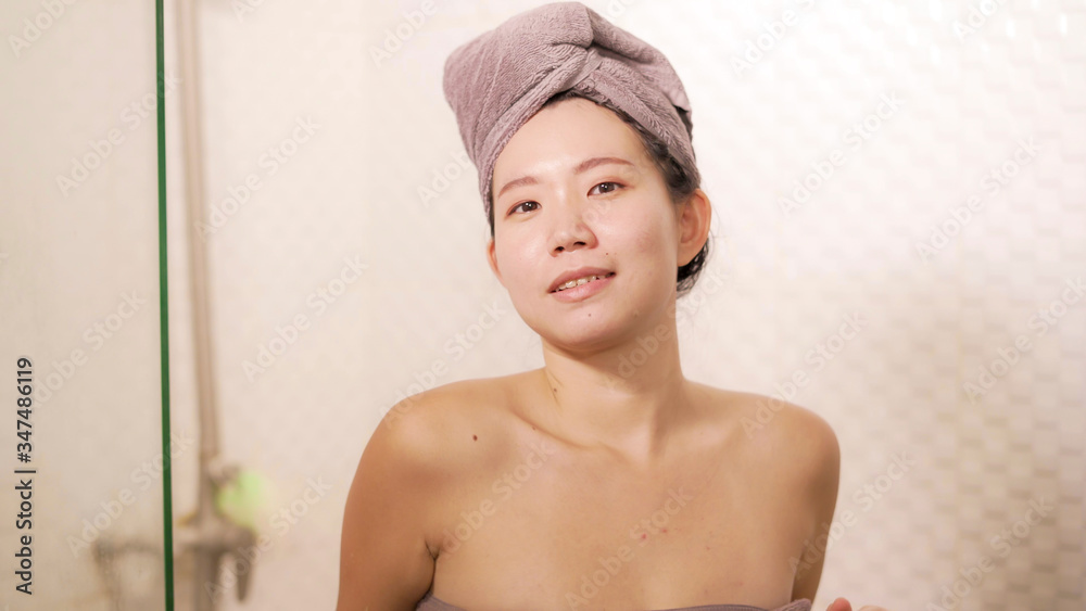 young beautiful and happy Asian Chinese woman with head wrapped in towel smiling fresh and cheerful after taking shower enjoying morning routine and hygiene young beautiful and happy Asian Chinese woman with head wrapped in towel smiling fresh and cheerful after taking shower enjoying morning routine and hygiene