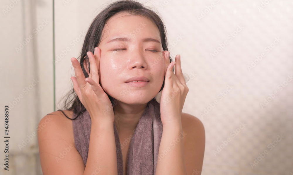 young happy and beautiful Asian Chinese woman applying moisturizer facial cream and beauty treatment at home bathroom in morning routine smiling cheerful and fresh young happy and beautiful Asian Chinese woman applying moisturizer facial cream and beauty treatment at home bathroom in morning routine smiling cheerful and fresh