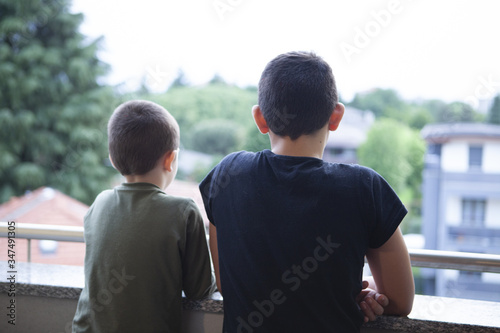 Two brothers children look out of them prison home during coronavirus pandemy

