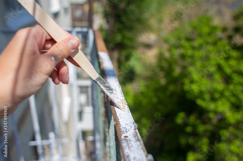The process of painting rusty peeling rods on the fence. Man paints a brush with a fence, hand closeup