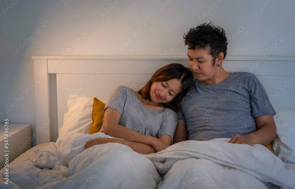 Smiling young Asian couple man and woman resting on the bed in bedroom. Happy family husband and wife relaxing and having a romantic moment together at home. Love, marriage and relationship concept. Smiling young Asian couple man and woman resting on the bed in bedroom. Happy family husband and wife relaxing and having a romantic moment together at home. Love, marriage and relationship concept.