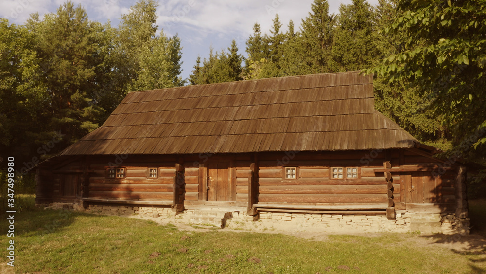 Long log house is surrounded by trees. Meadow in front of the house. Long log house is surrounded by trees. Meadow in front of the house.