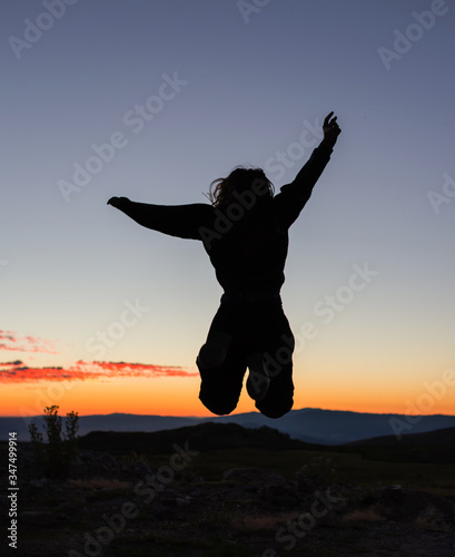 Silhouette of a woman jumping at sunrise