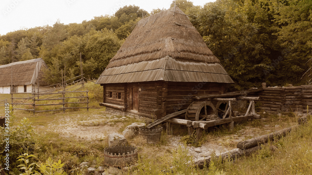 Wooden village house with big roof and historicalmill. Dense forest near it. Wooden village house with big roof and historicalmill. Dense forest near it.