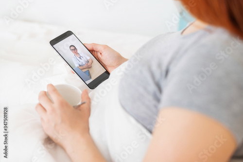 Woman on sick leave with a smartphone in her hands. A flu patient is watching a medical video blog. The doctor conducts an online consultation by phone. Bed rest.