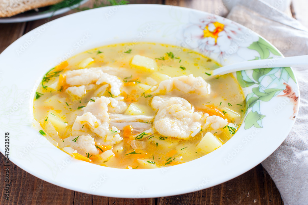 Homemade chicken soup with dumplings in a white plate, selective focus Homemade chicken soup with dumplings in a white plate, selective focus