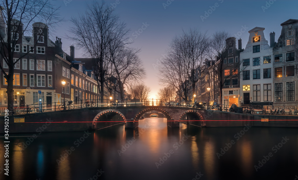 View over the Herengracht canal and the Vierheemskinderensluis bridge in Amsterdam on a quiet winter evening, just after sunset