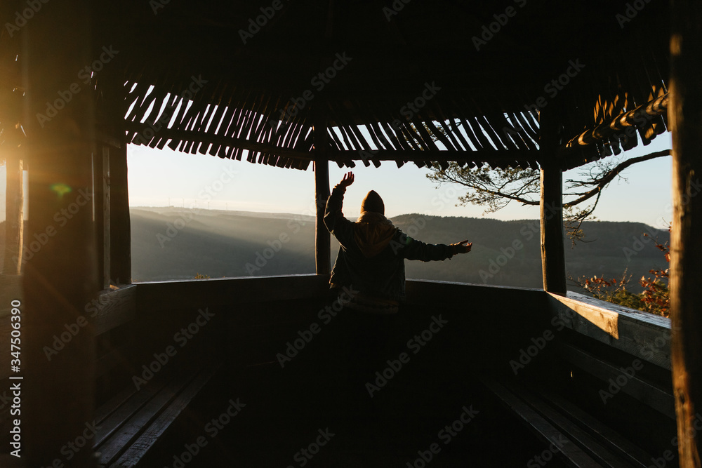 Woman with open arms at a kiosk in the forest