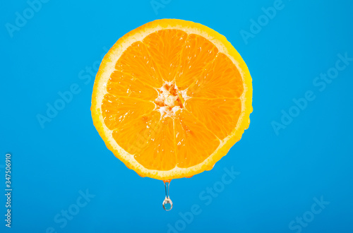 Swieza przekrojona pomarancza. Owoc na niebieskim tle. Kapiacy sok. Cytrusy w diecie odchudzajacej. Zrodlo witaminy c. Wegetarianski posilek. Dieta odchudzajaca.
