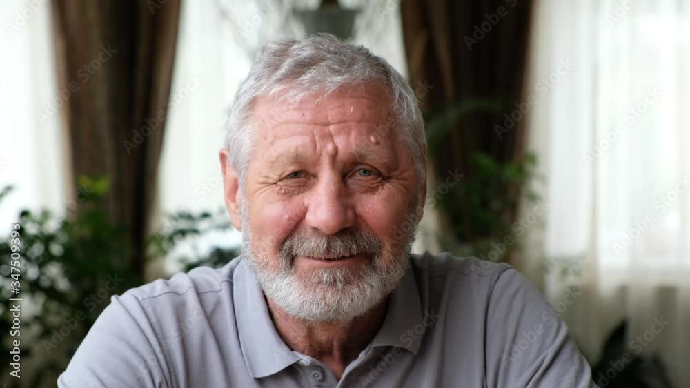 Senoir elderly man with kind happy face looking at camera, smiling and talking