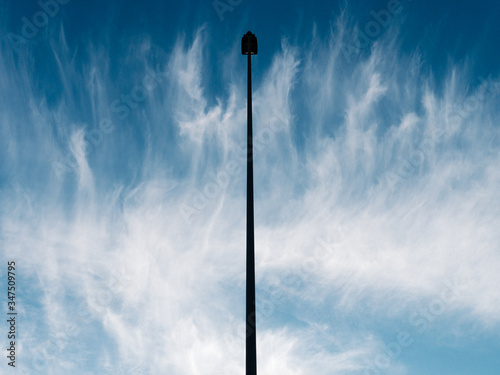 The light of the street on a background of blue sky. The vertical street light in the center of the image